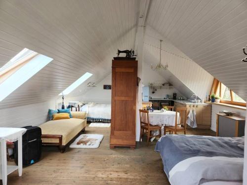 a attic room with a room with two beds and a table at Pirts māja in Engure