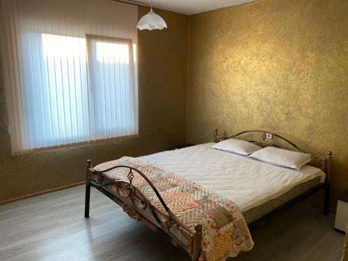 um quarto com uma cama com lençóis brancos e 2 janelas em Elena em Krushuna