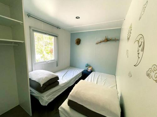 Habitación pequeña con 2 camas y ventana en Mobilhome climatisé 6 psn, en Lège-Cap-Ferret