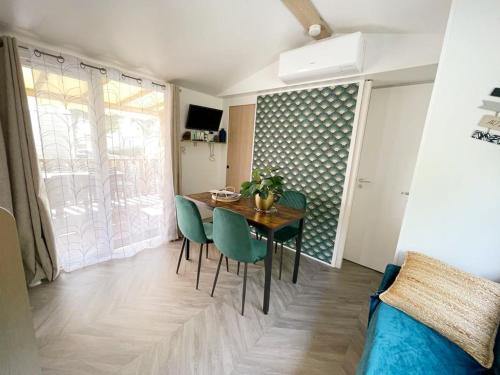 a dining room with a table and green chairs at Mobilhome climatisé 6 psn in Lège-Cap-Ferret