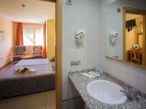 a bathroom with a sink and a bed and a mirror at El Pinche de Oro in Benicarló