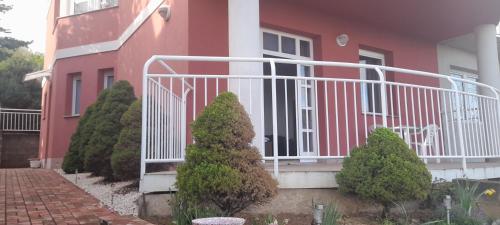 a pink house with a white railing and some bushes at Panoráma apartman in Pécs