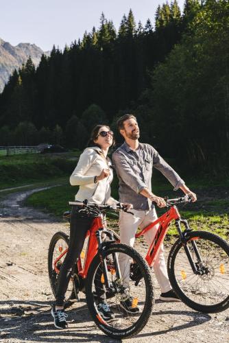 a man and woman riding bikes on a dirt road at Traumhotel Alpina Superior Adults only Hotel in Gerlos