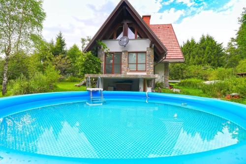 a house with a large swimming pool in front of a house at Sanjska Hiša Vojsko in Idrija