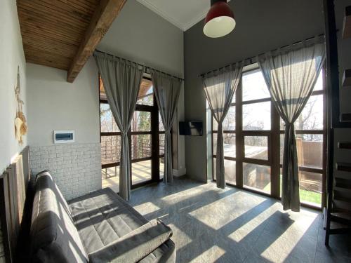 a living room with a couch and large windows at Апартаменты в доме у моря in Dzhubga