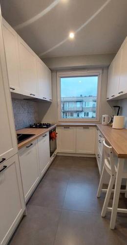 a kitchen with white cabinets and a large window at Przytulne mieszkanie w Olkuszu/ Cosy apartment in Olkusz in Olkusz