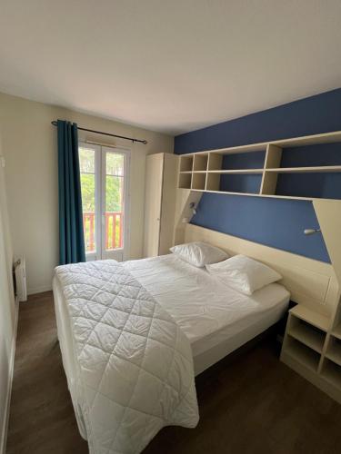 - une chambre avec un grand lit blanc et un mur bleu dans l'établissement Maison Pierre&Vacances*** Lacanau Océan, à Lacanau
