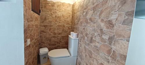baño con aseo y pared de piedra en Castra Vinaria, en Casarabonela