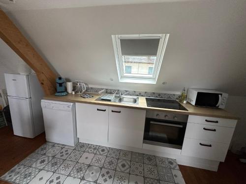 cocina con armarios blancos, fregadero y microondas en Superbe appartement proche centre ville, thermes en Bagnères-de-Bigorre