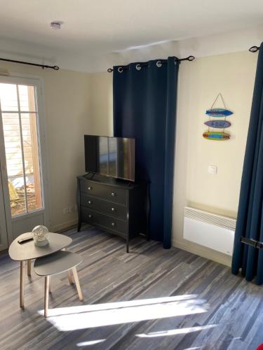 un salon avec une télévision et une table dans l'établissement Maison Pierre&Vacances*** Lacanau Océan, à Lacanau