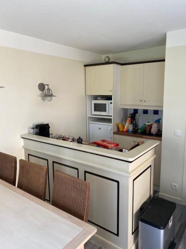 une cuisine avec un comptoir et une table avec des chaises dans l'établissement Maison Pierre&Vacances*** Lacanau Océan, à Lacanau
