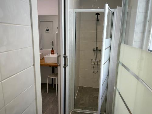 baño con ducha y puerta de cristal en Albergue SCQ, en Santiago de Compostela