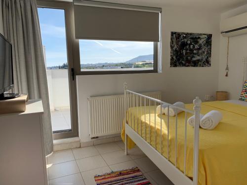 a bedroom with a bed with yellow sheets and a window at Melina Knossos Iraklio Crete in Áno Fortétsa