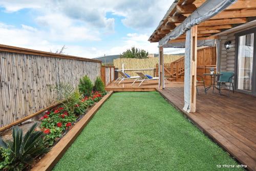 a small backyard with a wooden deck with a lawn at Suites Tuia in Had Nes
