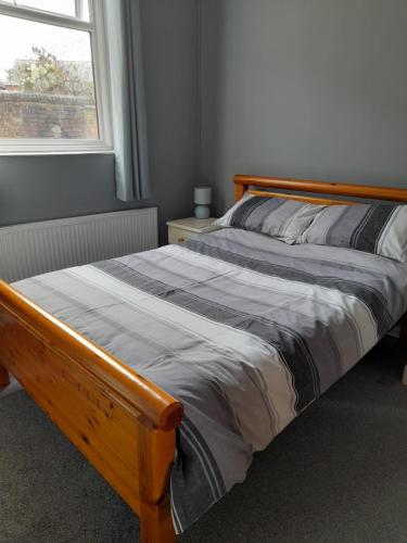 a bed with a wooden frame in a room with a window at Home from Home in Faversham