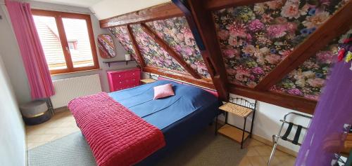 a small bedroom with a blue bed with a red blanket at Gaby et Georges in Beblenheim