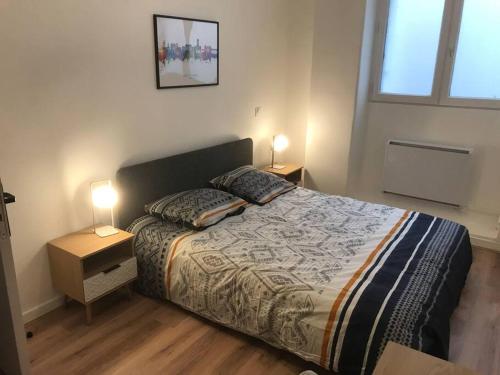 une chambre avec un lit avec deux lampes dessus dans l'établissement Appart’ entièrement rénové au centre ville St Étienne, à Saint-Étienne