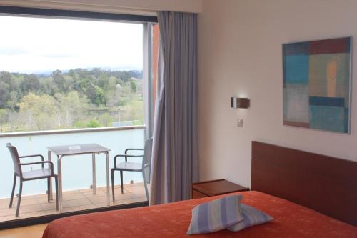 a bedroom with a bed and a balcony with a table and chairs at Hotel Dom Afonso - Monção in Monção