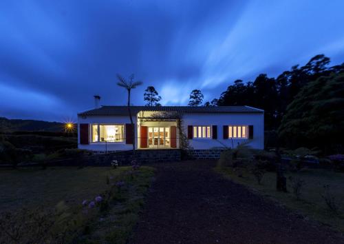 a small white house at night with the lights on at Lake View House in Sete Cidades