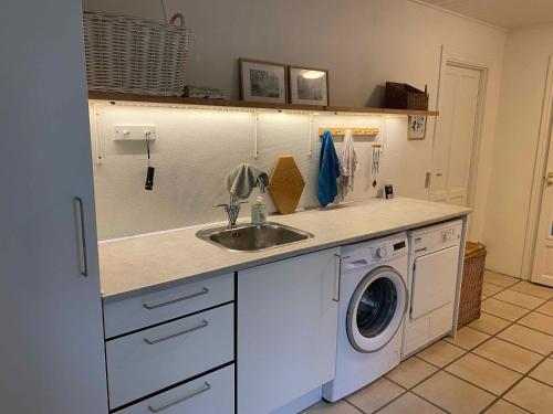 una cucina con lavandino e lavatrice di Idyllically Located Wooden House By The Forest, 2 a Viborg