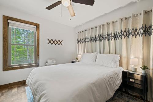 a white bedroom with a large bed and a window at Serra Stays - "Casa di Cresta" in Lake Lure