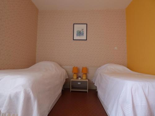 - 2 lits dans une chambre avec des draps blancs et des murs orange dans l'établissement A 2 pas du Port et de la Plage - Appartement 2 chambres - parking - Saint-Cyprien plage, à Saint-Cyprien