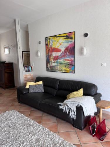 a black couch in a living room with a painting at Villa les Rosiers in Tallard