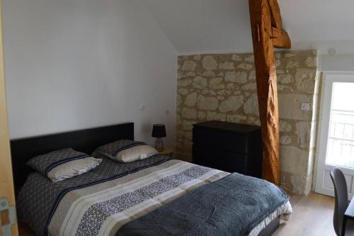 1 dormitorio con cama y pared de piedra en La Grange de l'Olive, en Chinon