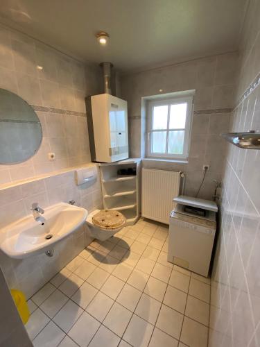 a white bathroom with a sink and a toilet at Haus Blaubär in Friedrichskoog