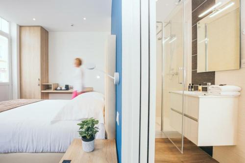 a room with a bed and a bathroom with a sink at Hôtel Villa Des 2 Caps in Wimereux