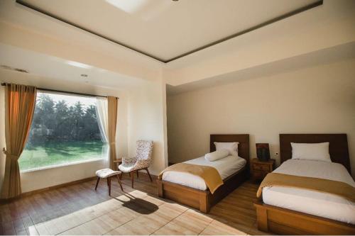 Escotel Villa Marga في تابانان: غرفة نوم بسريرين ونافذة كبيرة