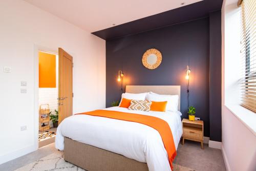 a bedroom with a large bed with an orange blanket at Stunning 2 Bed Apartment Sea Views and Parking in Worthing