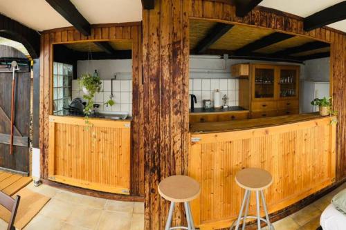 eine Küche mit Holzwänden und 2 Hockern in der Unterkunft Casa Ländli in Grenzach-Wyhlen