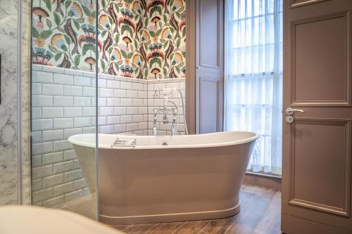 uma banheira na casa de banho com papel de parede floral em The Raeburn em Edimburgo