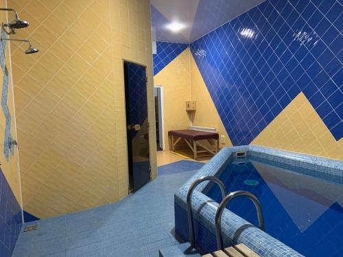 a bathroom with a swimming pool with blue and yellow tiles at Hetman Hotel in Kamianets-Podilskyi