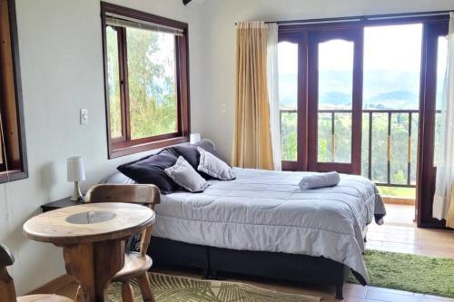1 dormitorio con cama, mesa y ventanas en La Rosaleda 3 - Hermosa finca en Paipa, en Paipa