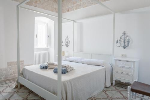 ein weißes Schlafzimmer mit einem Bett und einem Spiegel in der Unterkunft Trulli Harmonia con piscina - Alberobello in Alberobello