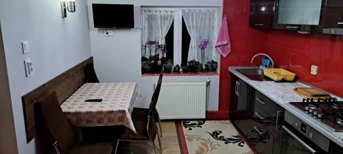 a small kitchen with a table and a refrigerator at Casa Diana Govora in Prăjila