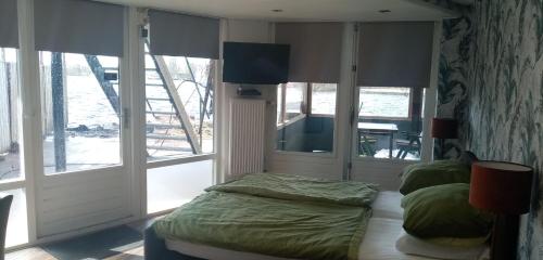1 dormitorio con 1 cama, TV y ventanas en B&B aan het water, en Earnewâld