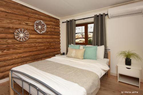 een bed in een kamer met een houten muur bij Suites Tuia in Had Nes