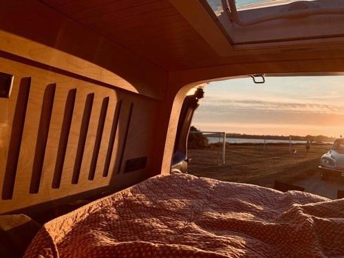 uma cama na parte de trás de uma carrinha com o pôr-do-sol em OsloCampervan em Oslo