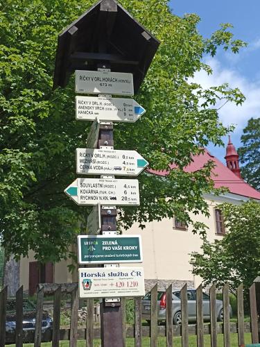a street sign with many signs on a pole at Skiapartma - Říčky v Orlických horách in Říčky