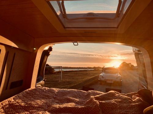 OsloCampervan في أوسلو: سيارة متوقفة في خلف سيارة مع غروب الشمس