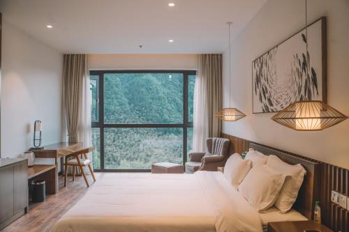 a hotel room with a large bed and a desk at Zhangjiajie National Park Nvue Resorts in Zhangjiajie