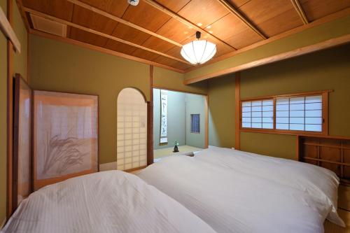 土莊町的住宿－島の風景に溶け込む、日本の伝統旅館「かんなから」，卧室设有2张白色的床和木制天花板。