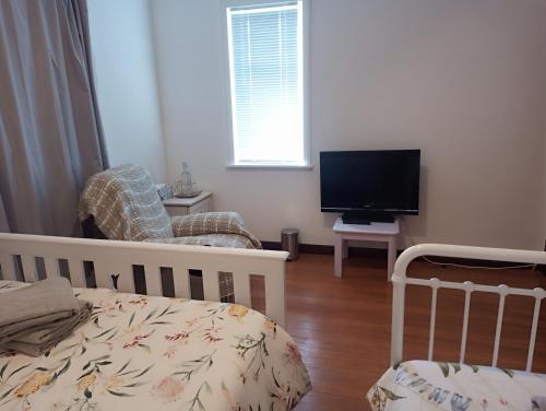 a bedroom with a crib and a flat screen tv at Little Gem - City Centre in Hamilton