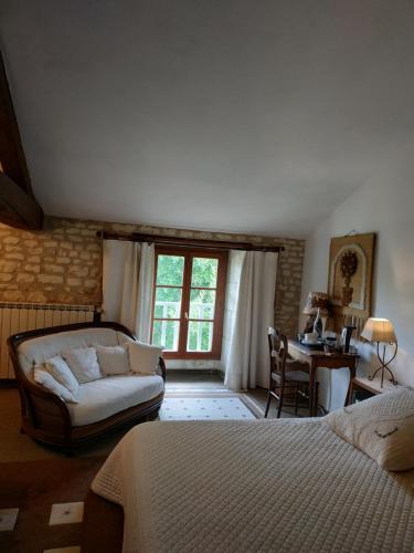 Schlafzimmer mit einem Bett, einem Schreibtisch und einem Fenster in der Unterkunft Le Clos des Fayes in Berthegon