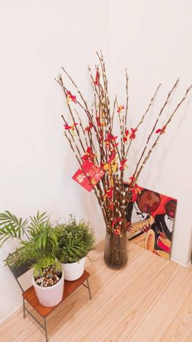 a vase with flowers on a table with two plants at Stay if you wish Homestay in Jiufen
