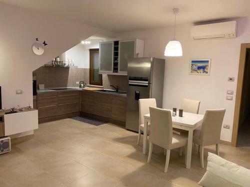 una cucina con tavolo, sedie e frigorifero di Appartamento al mare - Porto Recanati a Porto Recanati