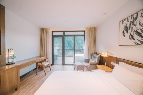 a hotel room with a bed and a desk at Zhangjiajie National Park Nvue Resorts in Zhangjiajie